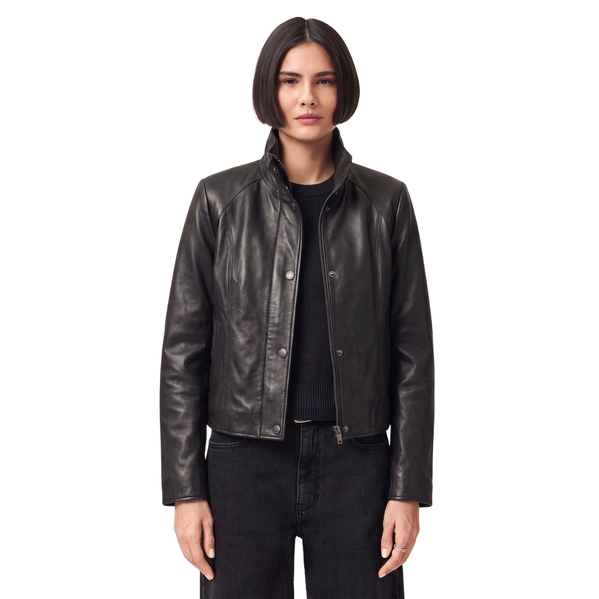Woman wearing black leather moto jacket with snap buttons and zipper, styled with dark jeans