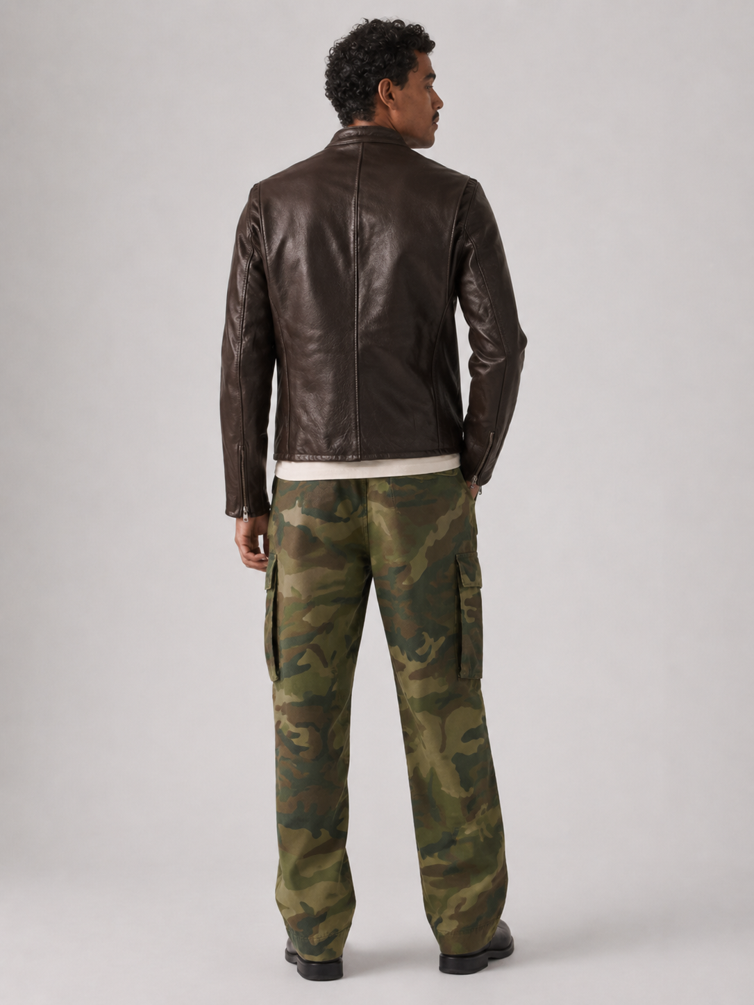 Man wearing brown leather jacket and camouflage cargo pants, back view