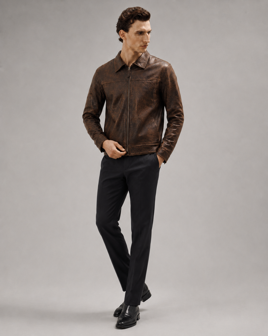 Men's brown leather jacket with zip front, paired with black dress pants and shoes, studio look