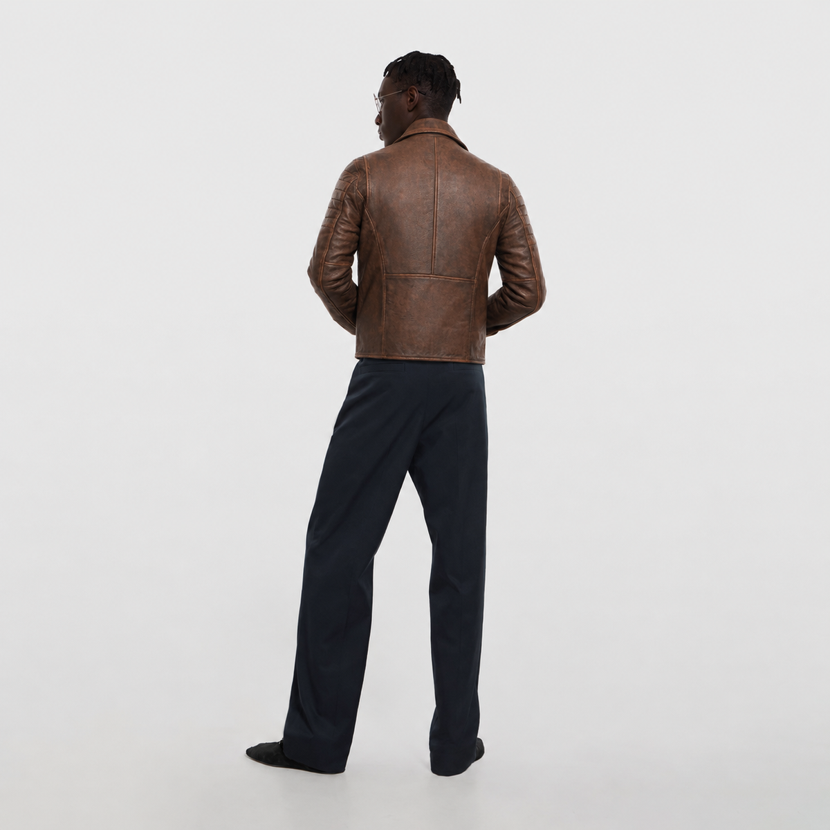 Men's brown leather jacket with quilted sleeves, back view, paired with dark trousers