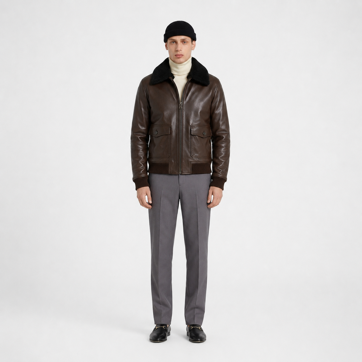 Men's brown leather bomber jacket with shearling collar, styled with turtleneck and gray trousers
