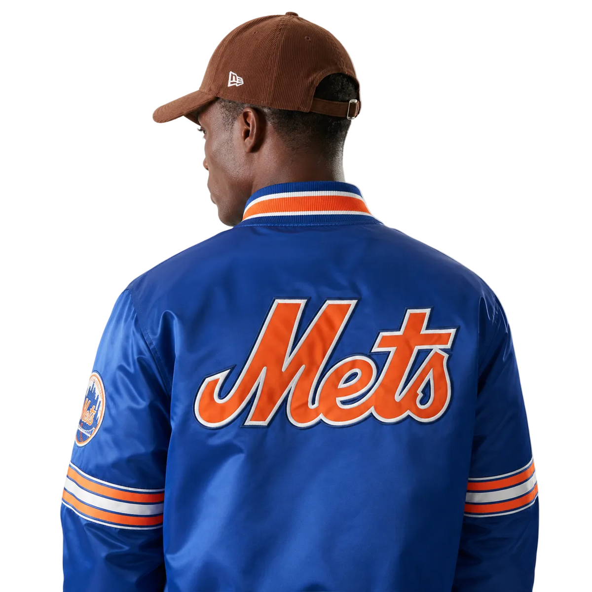 Blue Mets varsity jacket with orange script logo, striped sleeves, and team patch, worn with brown cap