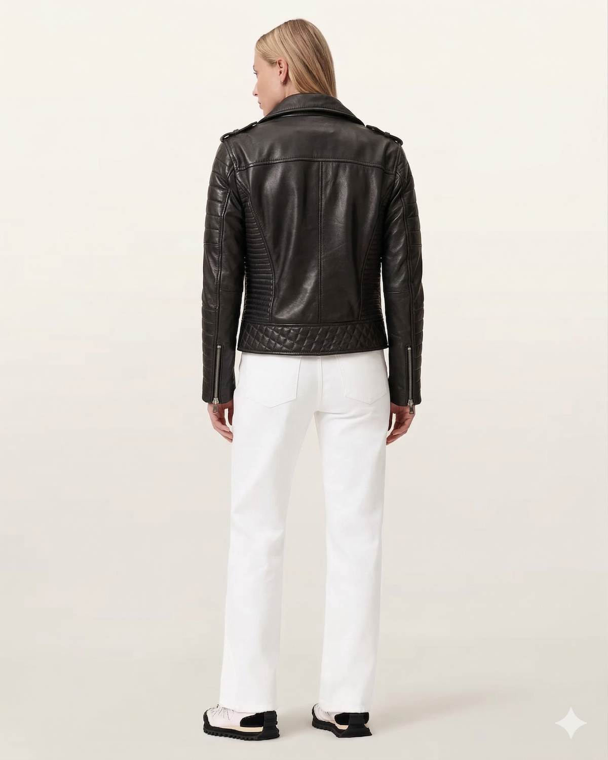 Black leather moto jacket with quilted back and zipper details, paired with white pants