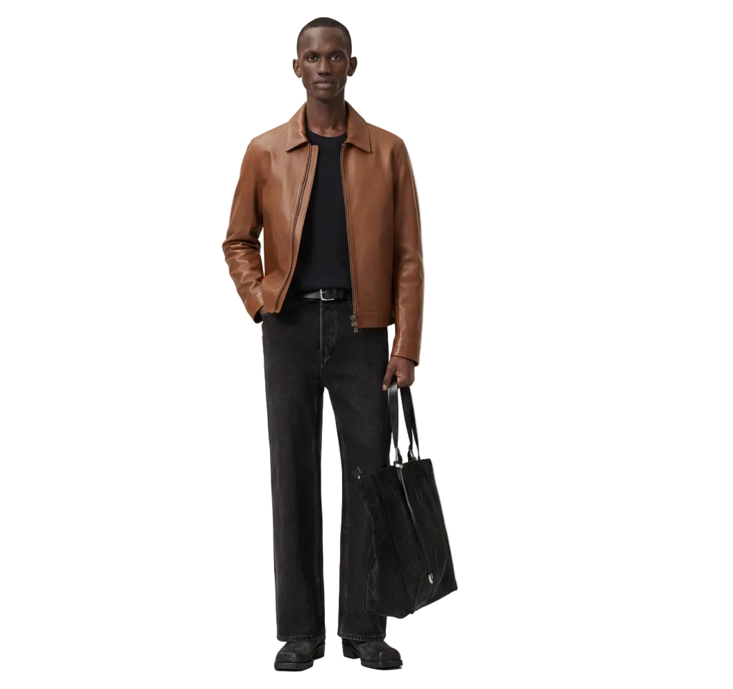 Man wearing brown leather jacket, black jeans, and carrying tote bag, stylish casual outfit