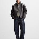 Men's black leather jacket with button front, paired with dark denim jeans and keychain accessory