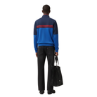 Men's color-block sweater with red stripes, black jeans, and tote bag, back view