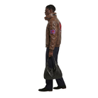 Man wearing brown leather jacket with patches, holding black bag, stylish urban outfit