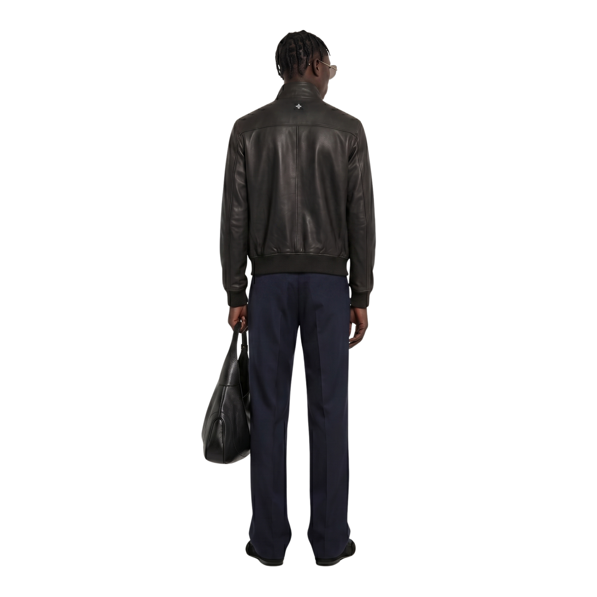 Man wearing black leather jacket and navy trousers, holding black bag, back view