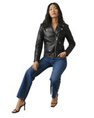 Woman in black leather moto jacket, blue jeans, and heels, posing confidently