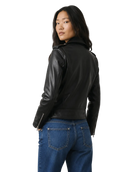 Woman wearing black leather moto jacket with zipper details, paired with blue jeans, back view