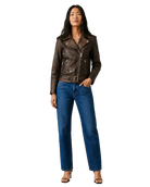 Woman in brown leather moto jacket with belt, paired with blue wide-leg jeans and heels