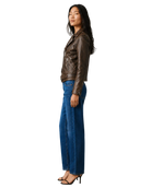 Woman in brown leather moto jacket, blue wide-leg jeans, and black heels, side view