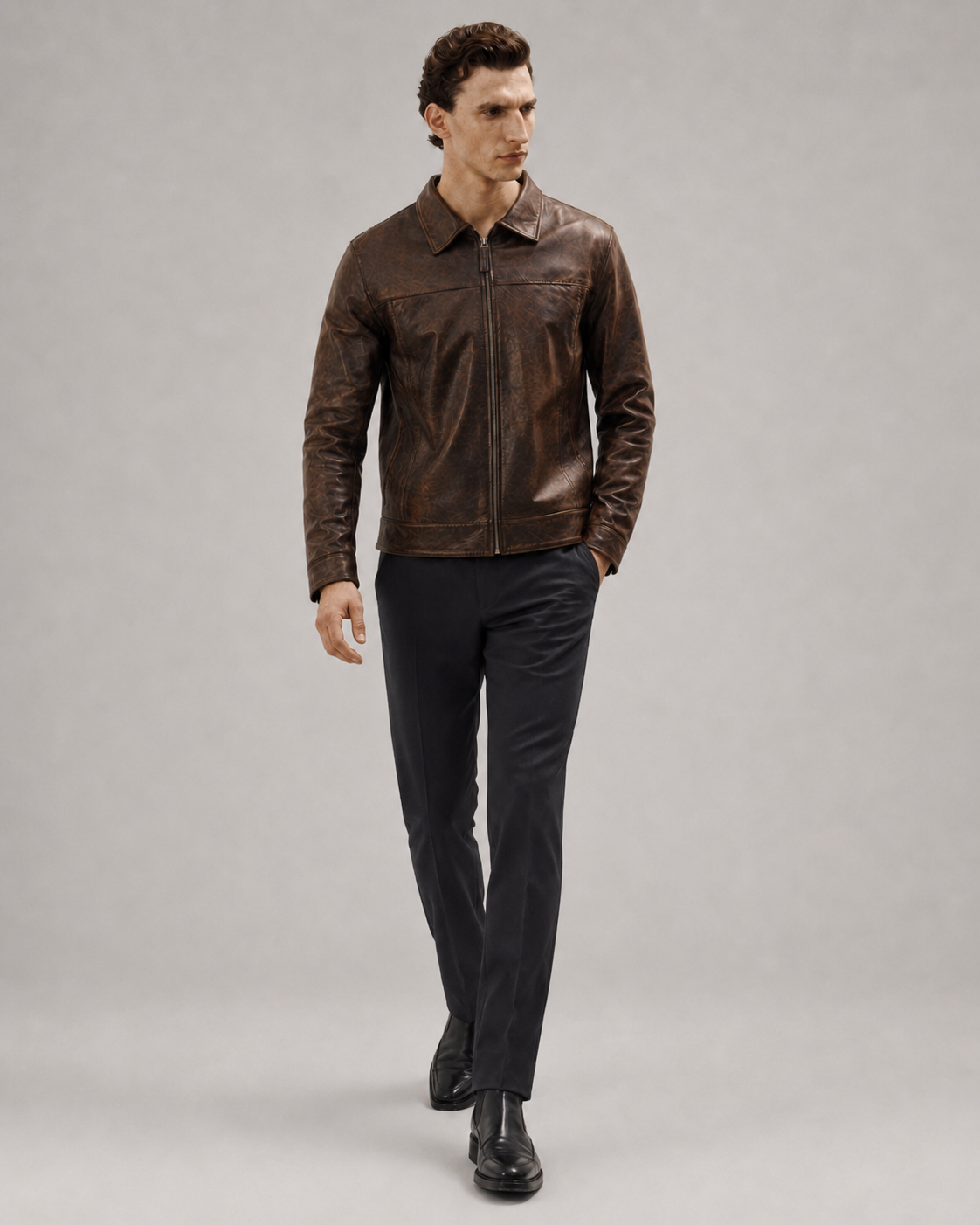 Men's brown leather jacket with zip front, styled with black trousers and dress shoes for a classic look
