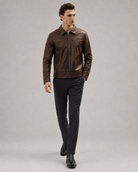 Men's brown leather jacket with zip front, styled with black trousers and dress shoes for a classic look