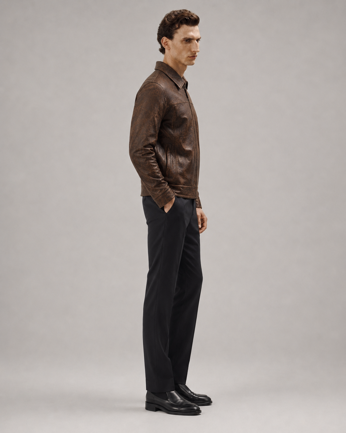 Man in brown leather jacket with black trousers and dress shoes, side profile
