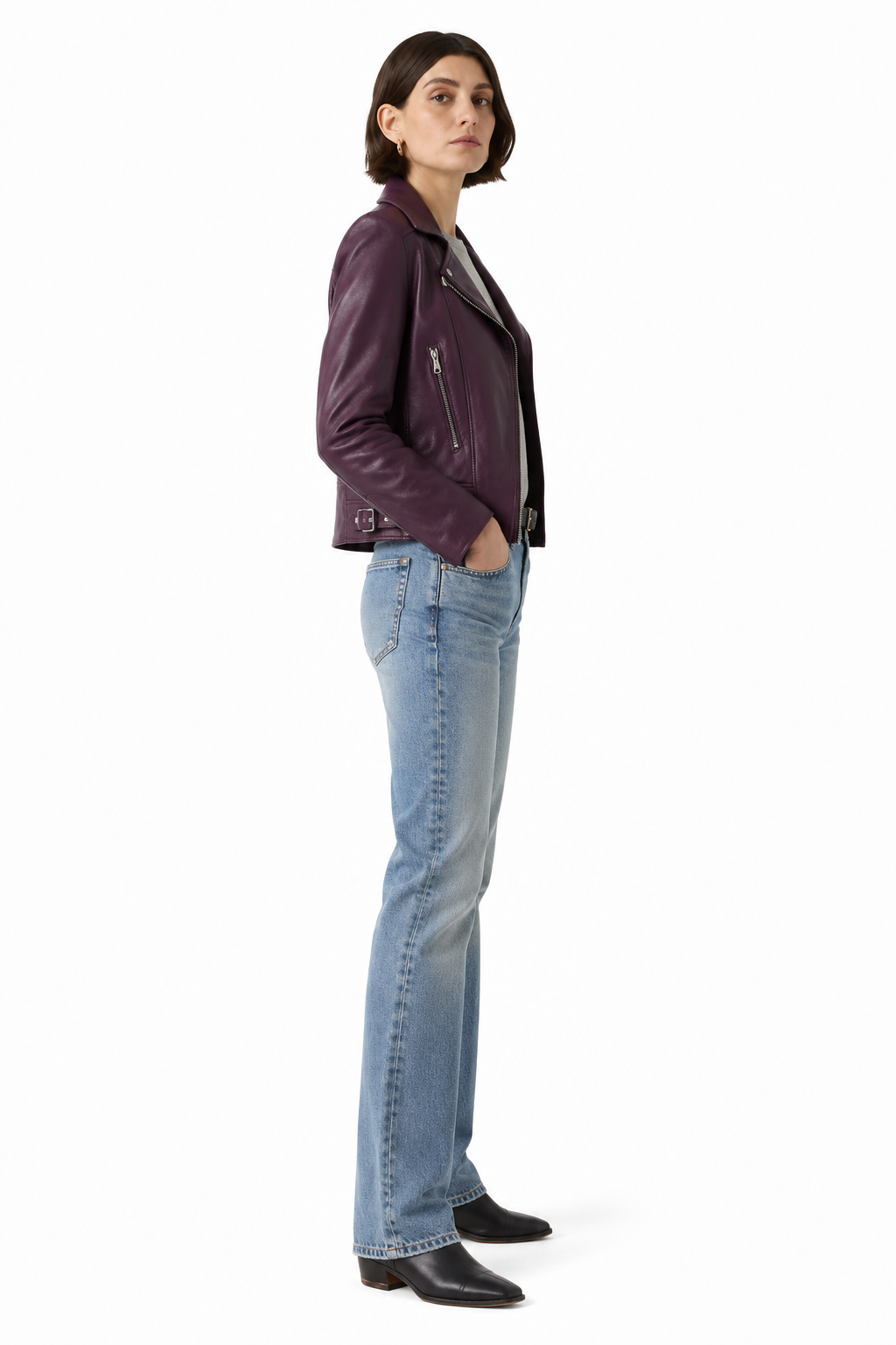 Woman in purple leather jacket, blue jeans, and black boots, side profile