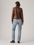 Brown leather jacket with blue jeans and black boots, back view