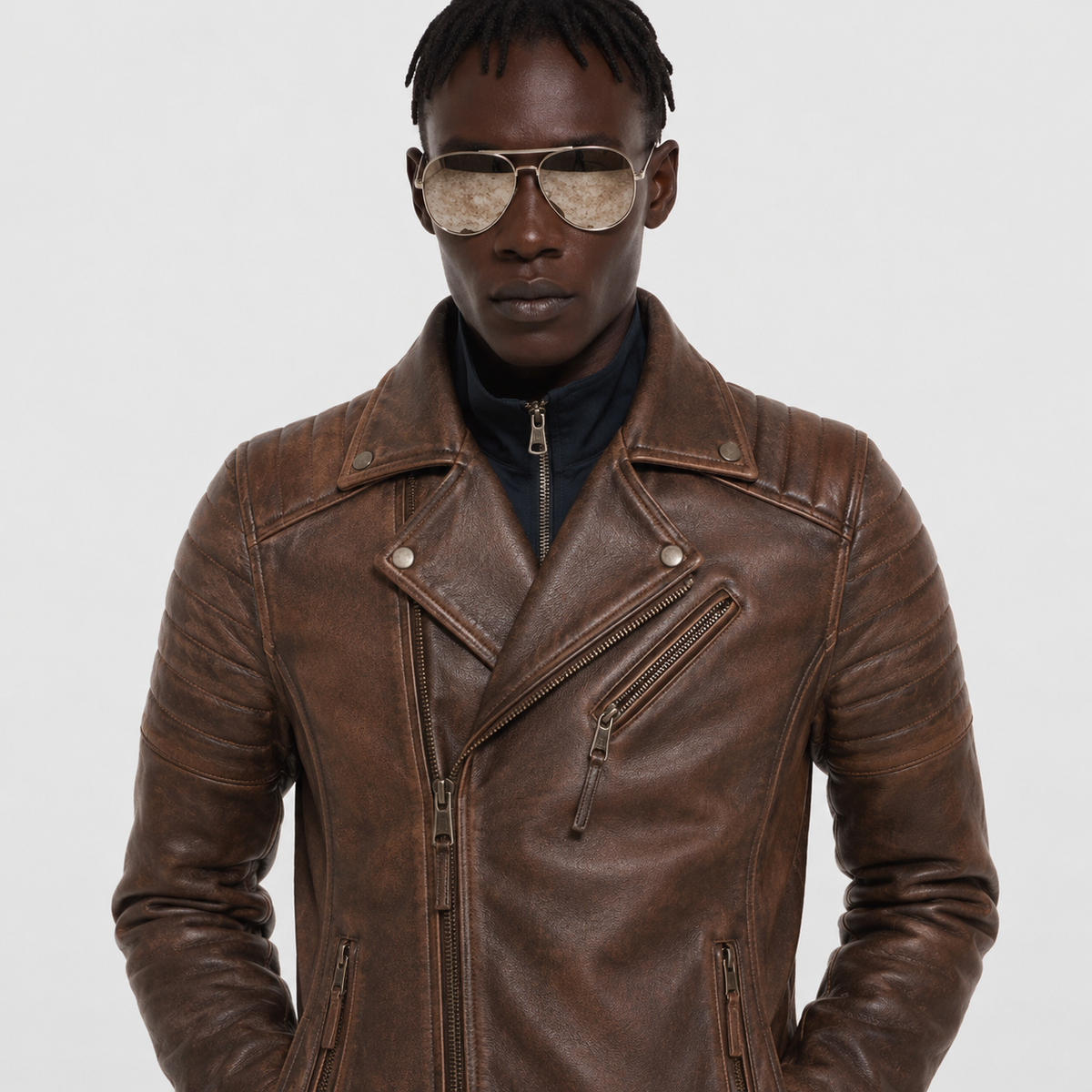 Men's brown leather biker jacket with zippers and snap buttons, styled with aviator sunglasses