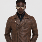 Men's brown leather biker jacket with zippers and snap buttons, styled with aviator sunglasses