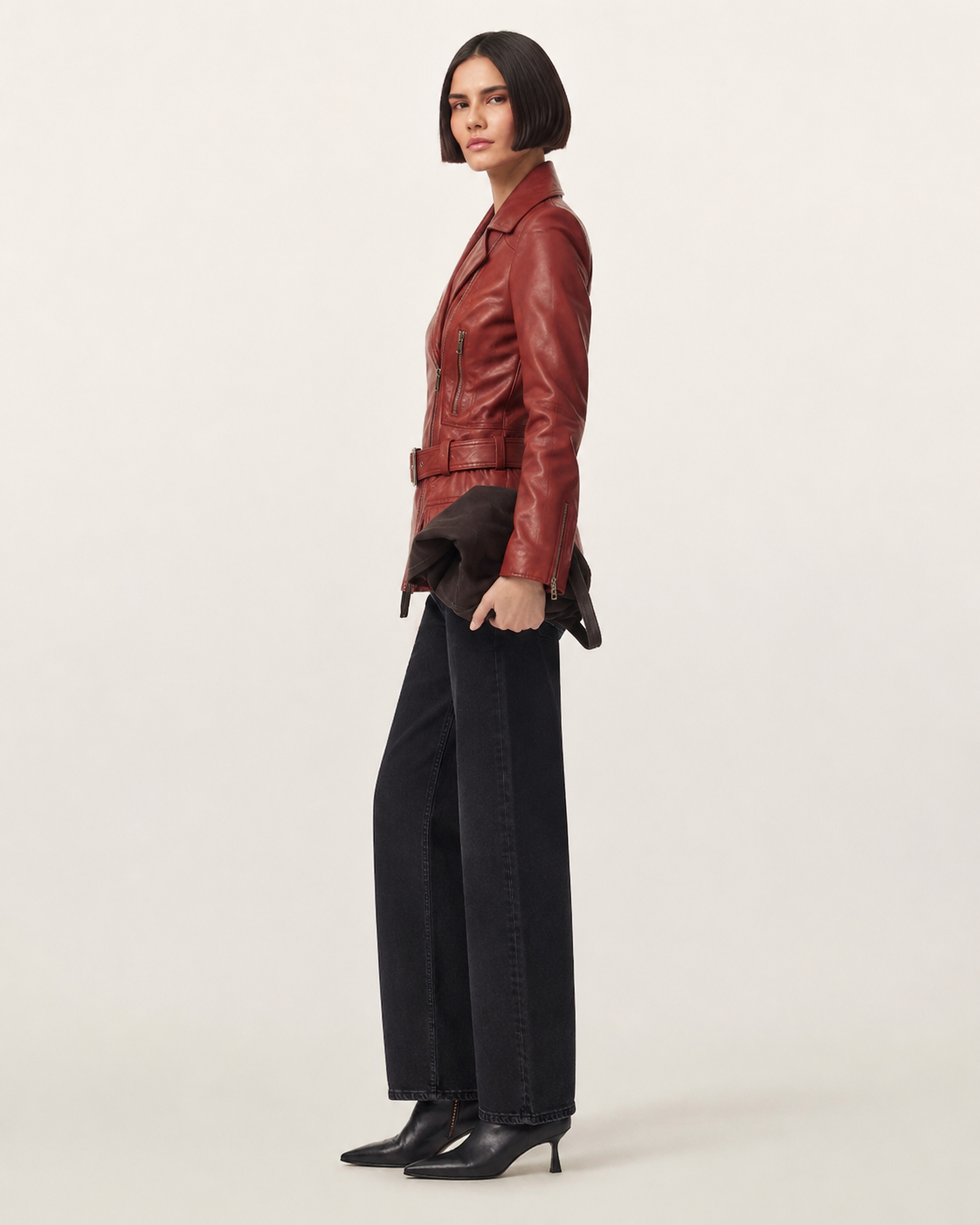 Woman in red leather jacket with belt, black wide-leg jeans, and pointed heels
