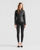 Woman in black leather moto jacket with zipper details, paired with skinny jeans and heels