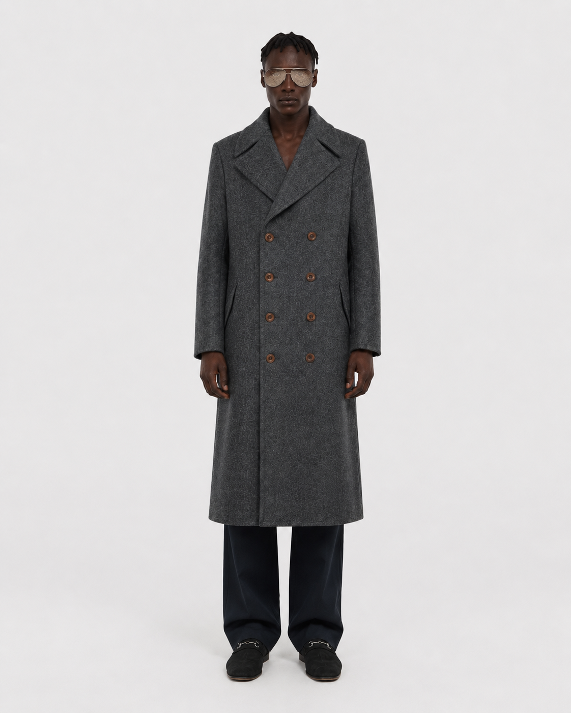 Men's gray double-breasted wool coat with patterned texture, worn with dark trousers and loafers
