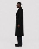 Man in black double-breasted wool coat, side profile, minimalist studio look