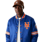 Blue New York Mets satin varsity jacket with orange logo and striped sleeves, worn with brown cap