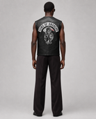 Black leather vest with Sons of Anarchy skull logo, worn by man in dark pants, back view