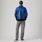 Man wearing blue leather jacket, gray jeans, and black sneakers from behind