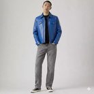 Man wearing vibrant blue leather jacket with patch, gray jeans, and black sneakers for casual streetwear style