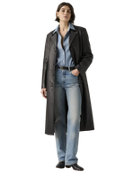 Woman wearing black leather trench coat over denim shirt and jeans