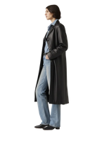 Woman in black leather coat, blue jeans, and black boots, side profile