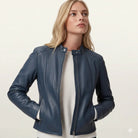 Woman wearing navy blue leather moto jacket with zipper details over cream sweater