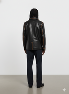 Black leather jacket with contrast stitching, back view on model wearing dark trousers