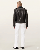 Black leather moto jacket with quilted back and zipper details, paired with white pants