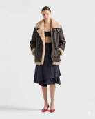 Women's shearling coat with faux fur lining, paired with navy pleated skirt and red heels
