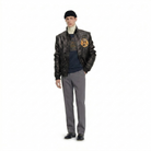 Men's black leather bomber jacket with patch, styled with turtleneck, graphic tee, gray trousers, and loafers