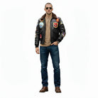 Man wearing black leather bomber jacket with patches, jeans, and aviator sunglasses