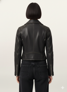 Black leather moto jacket with quilted shoulders and back zipper details, worn with dark jeans
