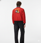 Red bomber jacket with Baywatch graphic on back, worn with black jeans