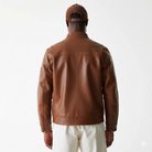 Brown leather jacket with zipper cuffs, worn by man in cap, back view