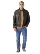 Man wearing dark brown leather jacket, beige shirt, blue jeans, and black sneakers