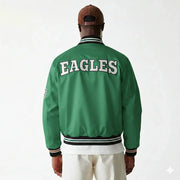 Green Eagles varsity jacket with white lettering, striped cuffs and collar, worn by man in cap