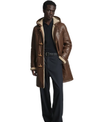 Men's brown shearling coat with hood, toggle closures, and wool lining, styled with navy pants and sweater