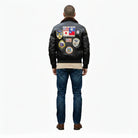 Men's black leather bomber jacket with vintage aviation patches, shearling collar, and classic fit