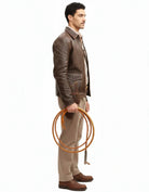 Man in brown leather jacket holding coiled rope, side profile, casual outdoor style