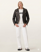 Woman in black leather biker jacket, white sweater, and white jeans, stylish casual outfit