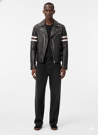 Men's black leather biker jacket with striped sleeves, paired with dark jeans and casual shoes