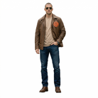 Man wearing brown leather jacket with patch, sunglasses, beige tee, blue jeans, and brown boots